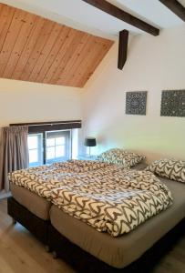 a bedroom with a large bed and wooden ceilings at Klakbaan 14 in IJzendijke