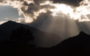 a ray of sunlight coming through the clouds over a mountain at McGregor Mountain Lodge in Estes Park