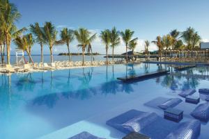 een groot zwembad met stoelen en palmbomen bij Riu Reggae - Adults Only - All Inclusive in Montego Bay