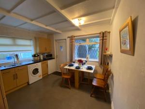 a kitchen with a table and a sink and a stove at Quiet secluded two bedroom bungalow with parking in Cleveleys