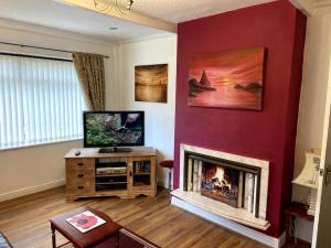 a living room with a fireplace and a flat screen tv at Quiet secluded two bedroom bungalow with parking in Cleveleys