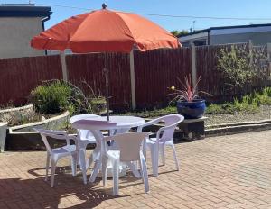 a table and chairs and an umbrella on a patio at Quiet secluded two bedroom bungalow with parking in Cleveleys