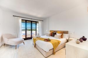 a white bedroom with a bed and a chair at VACATION MARBELLA I Aldea Blanca, Luxury Duplex, Sea View, Walking Distance to Puerto Banus in Marbella