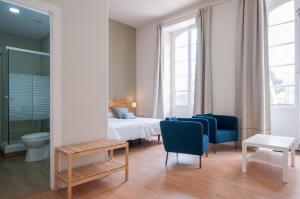 a bedroom with a bed and two blue chairs at Traditional Triana House with 9 en-suite Bedrooms in Las Palmas de Gran Canaria