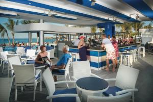 un grupo de personas sentadas en un bar en la playa en Riu Reggae - Adults Only - All Inclusive, en Montego Bay