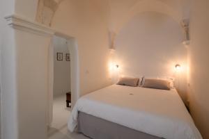 um quarto branco com uma grande cama branca e 2 almofadas em moma Ostuni Boutique Home em Ostuni