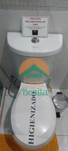 a white toilet with a sign on top of it at Hotel Casa Bonita in Campo Grande
