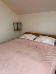 een slaapkamer met een groot bed met roze lakens en kussens bij Apartman Flora in Novi Grad