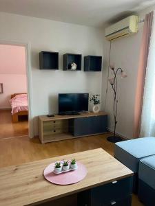 een woonkamer met een tafel en een televisie bij Apartman Flora in Novi Grad