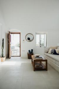 a white living room with a couch and a table at Kalyva Cycladic house - Oia Santorini in Oia
