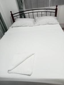 タクロバンにあるViner's Innの白いベッド(黒枠、白い枕付)