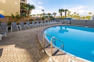 a swimming pool with lounge chairs next to a building at Nautilus 1203 - Gulf Front 2 Bedroom! 2nd Floor! Free Beach Service March to October in Fort Walton Beach