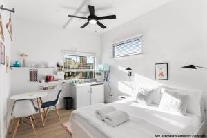 斯科茨Micro Studio with balcony & pool view - Walk to OT的一间带床和桌子的白色卧室