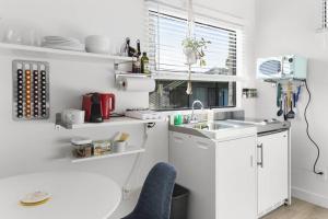 a white kitchen with a sink and a window at Micro Studio with balcony & pool view - Walk to OT in Scottsdale
