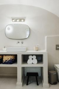 a white bathroom with a sink and a mirror at Kalyva Cycladic house - Oia Santorini in Oia