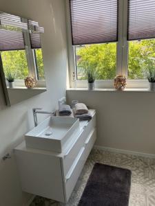 ein weißes Badezimmer mit einem Waschbecken und zwei Fenstern in der Unterkunft Außergewöhnlich Ferienwohnung im Villenviertel in Wilhelmshaven