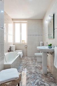 y baño blanco con bañera, lavamanos y bañera. en Genteel Home Ático Gran Capitán en Granada