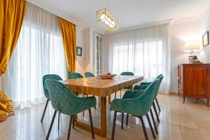 a dining room with a wooden table and green chairs at Genteel Home Martinez Campos in Granada