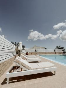 a pool with two lounge chairs next to a swimming pool at Hotel Thirasia in Fira
