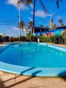 a large blue swimming pool with chairs and palm trees at Soul Lounge Hostel in São Luís