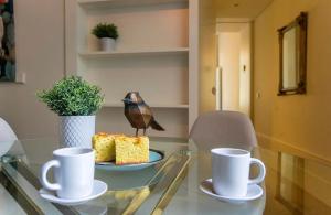 un oiseau assis sur une table en verre avec deux tasses dans l'établissement Inspiring City Center 1BR Apartment, à Porto