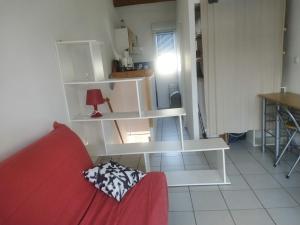 uma sala de estar com um sofá vermelho e prateleiras brancas em PALAVAS STUDIO AVEC BALCON ET PARKING em Palavas-les-Flots