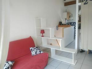 ein Wohnzimmer mit einer roten Couch und einem weißen Bücherregal in der Unterkunft PALAVAS STUDIO AVEC BALCON ET PARKING in Palavas-les-Flots