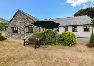 a bench and an umbrella in front of a house at Maes Mihangel in Llanfihangel-y-Pennant