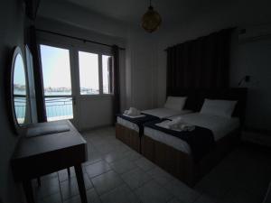 een slaapkamer met 2 bedden, een bureau en een raam bij Omiros rooms in Chios