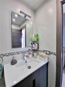 La salle de bains blanche est pourvue d'un lavabo et d'un miroir. dans l'établissement Cabo Cervera primera linea apartamento de lujo, à Torrevieja