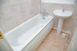 a bathroom with a sink and a bath tub next to a white sink at White House in Netherton