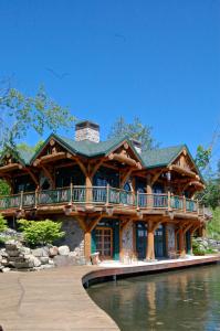 a large log house with a deck on the water at Oneida Lodge North in Cooperstown