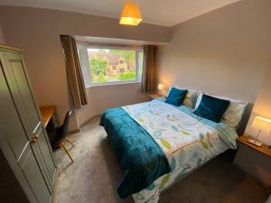 a bedroom with a bed with blue pillows and a window at 10 Tarleton Avenue, Woodhall Spa in Woodhall Spa