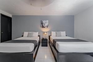 two beds in a room with white walls at Hotel Eclipse Mérida in Mérida