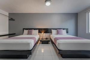 a bedroom with two beds and a table in it at Hotel Eclipse Mérida in Mérida