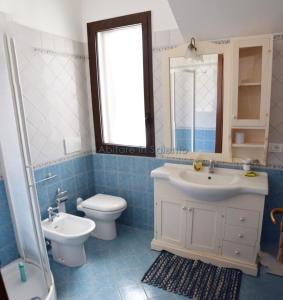 bagno con lavandino, servizi igienici e specchio di Villetta con terrazzo antistante a Marina di Leuca