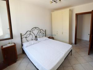 - une chambre avec un grand lit blanc et un miroir dans l'établissement Villetta con terrazzo antistante, à Marina di Leuca