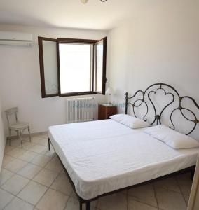 - une chambre avec un grand lit blanc et une fenêtre dans l'établissement Villetta con terrazzo antistante, à Marina di Leuca