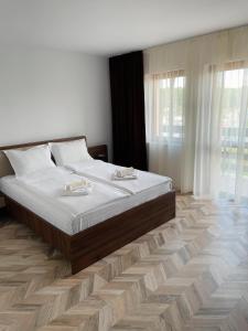 1 dormitorio con 1 cama grande con sábanas blancas en Pensiune Restaurant Indus, en Ocna Sibiului