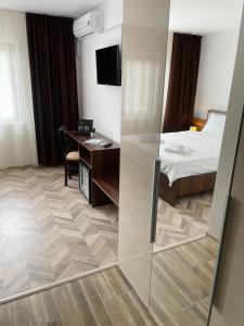 Habitación de hotel con cama, escritorio y habitación en Pensiune Restaurant Indus, en Ocna Sibiului