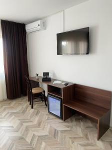 a room with a desk with a television and a table at Pensiune Restaurant Indus in Ocna Sibiului