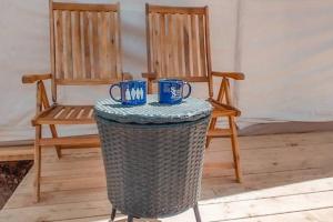 Dos sillas y una mesa con dos tazas azules. en Silver Spur Homestead Luxury Glamping -The Tombstone, en Tombstone