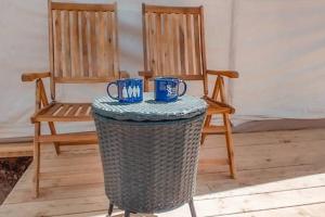 two chairs and a table with two blue cups on it at The Tombstone Tent in Tombstone