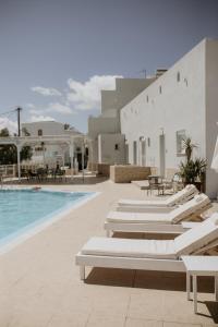 einen Pool mit Chaiselongues neben einem Gebäude in der Unterkunft Hotel Thirasia in Fira