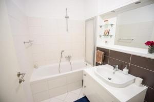 ein weißes Badezimmer mit einem Waschbecken, einer Badewanne und einer Dusche in der Unterkunft Apartment Zara White in Zadar