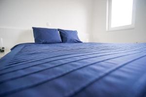 ein blaues Bett mit blauer Bettwäsche und einem Fenster in der Unterkunft Apartment Zara White in Zadar