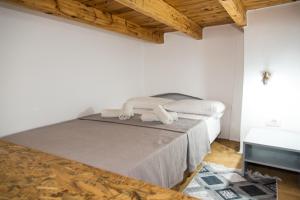Cama en habitación blanca con techo de madera en Mike's Guesthouse, en Lakkíon