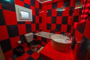 a red and black tiled bathroom with a sink and toilet at Sandscape Serenity S2 in Volos