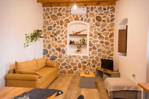 sala de estar con sofá y pared de piedra en Mike's Guesthouse, en Lakkíon