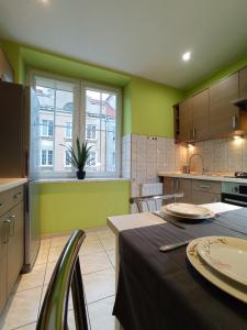 a kitchen with green walls and a table with plates on it at Studio Art Deco - Starówka - Old Town - AZW Gdańsk in Gdańsk